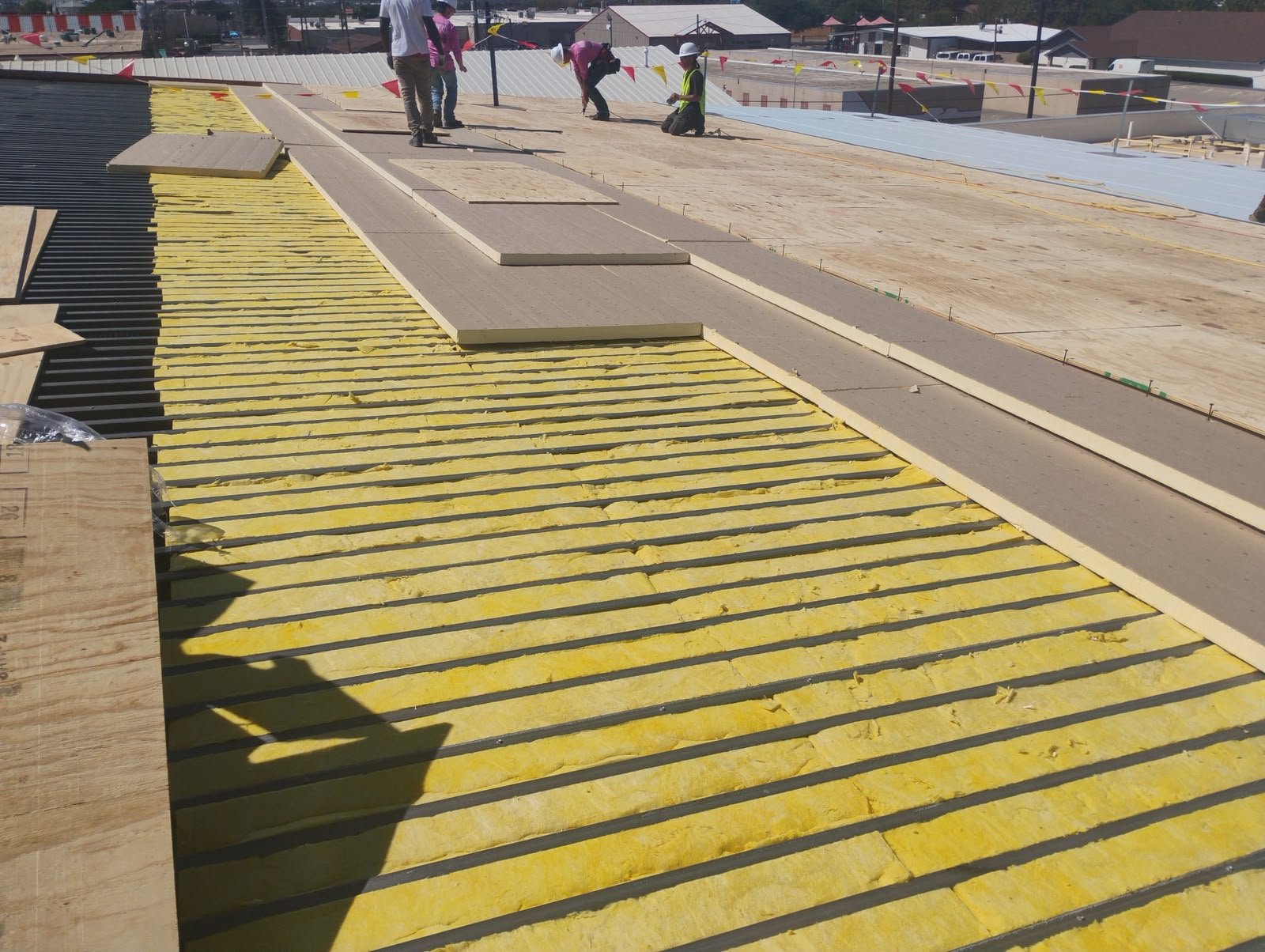 Crew installing insulation and cover board on a commercial roof deck