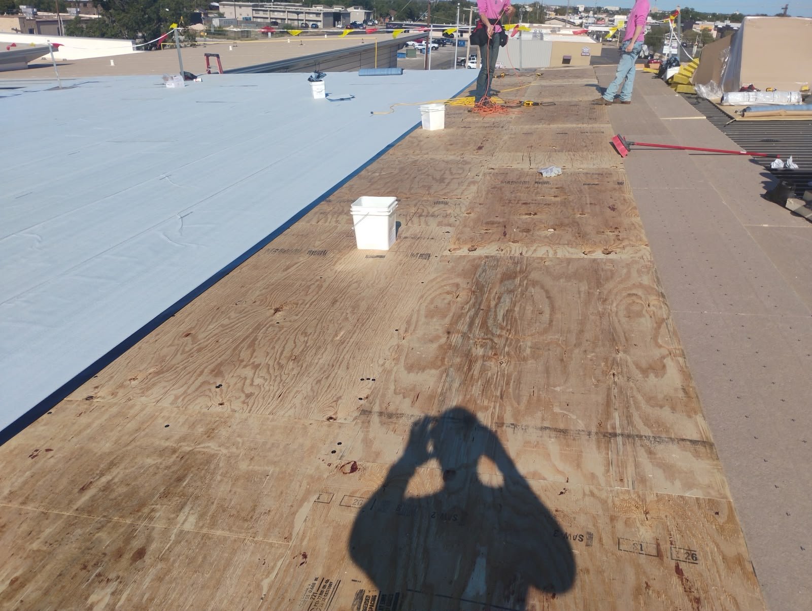Roofing crew applying membrane over recover board on a low-slope roof